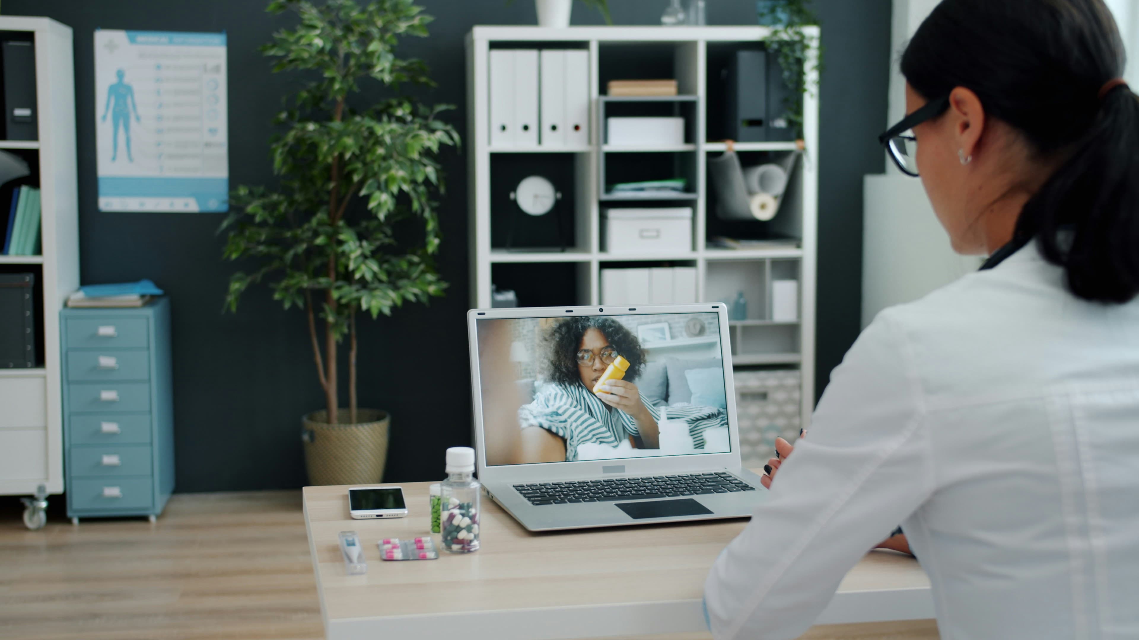 A doctor using a laptop for an online consultation with an African patient